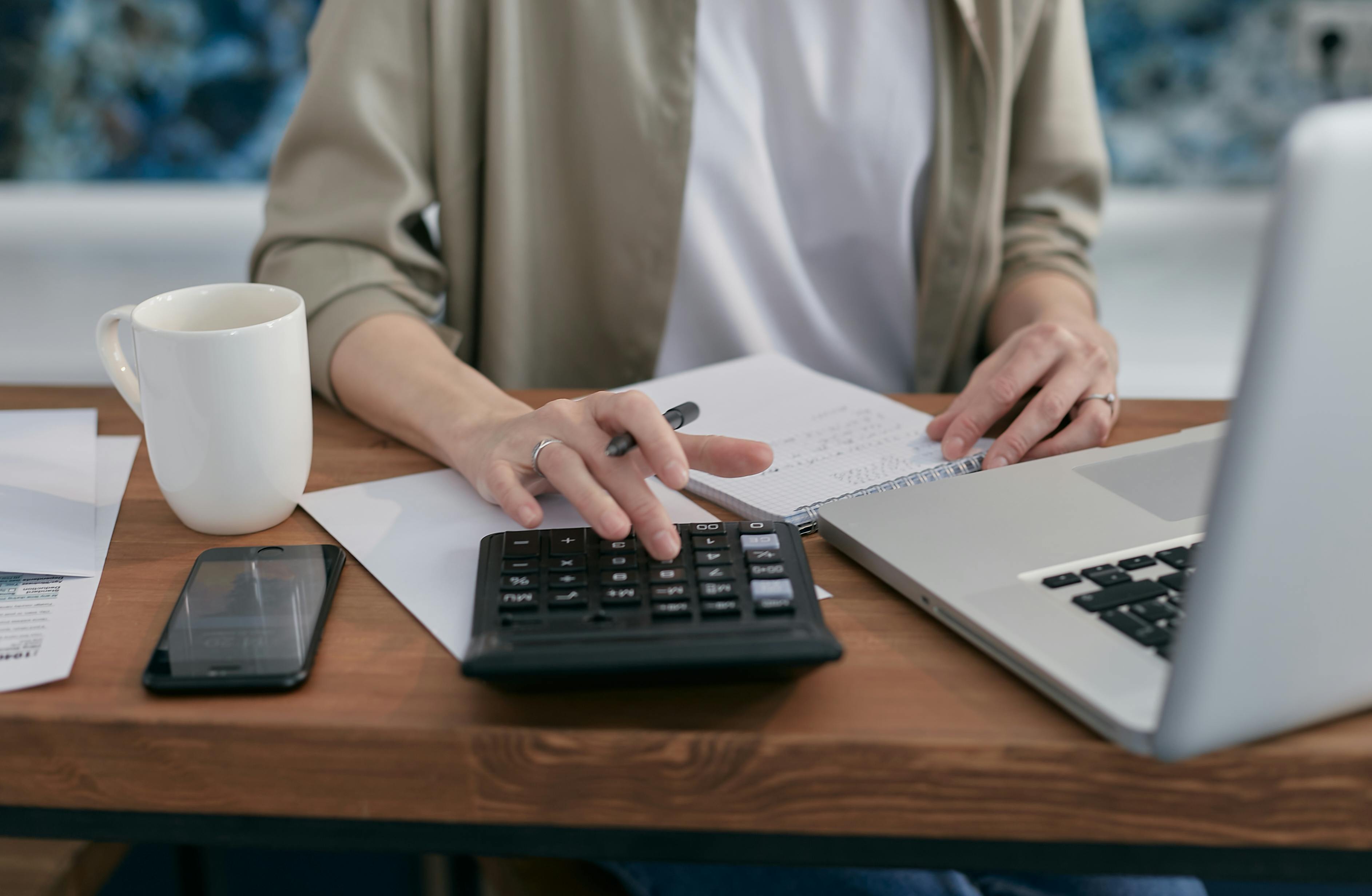 Student sitting at a desk counting results with a laptop and calculator